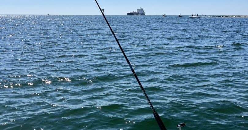Angler fishing from boat on open ocean waters with ship horizon