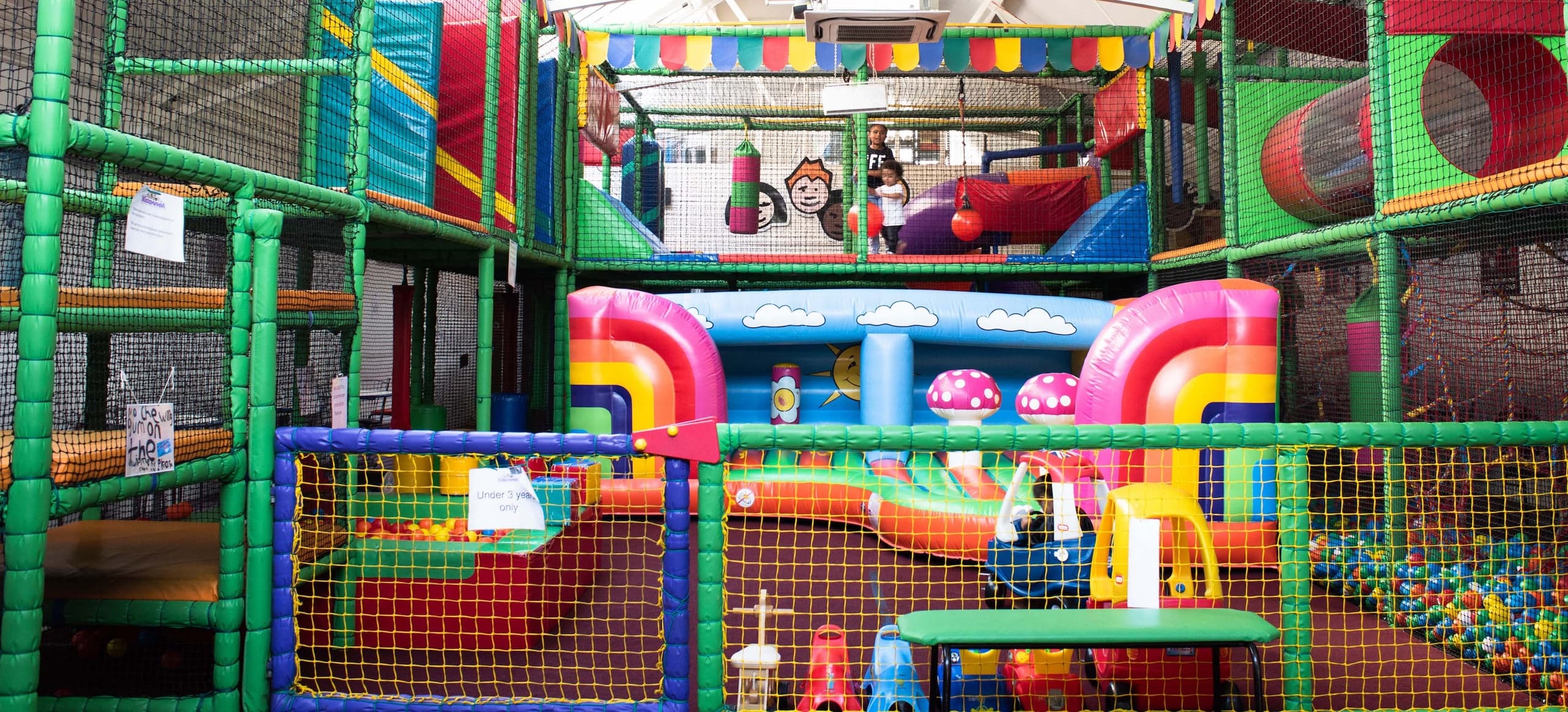 Kids playing in indoor soft-play playground with colorful ball pit