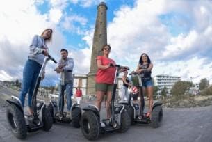 Segway tour group riding along coastal promenade by lighthouse