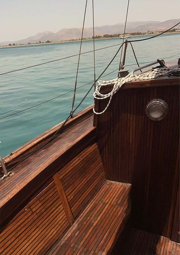 Wooden sailboat cockpit and deck seating with Aegean sea in background