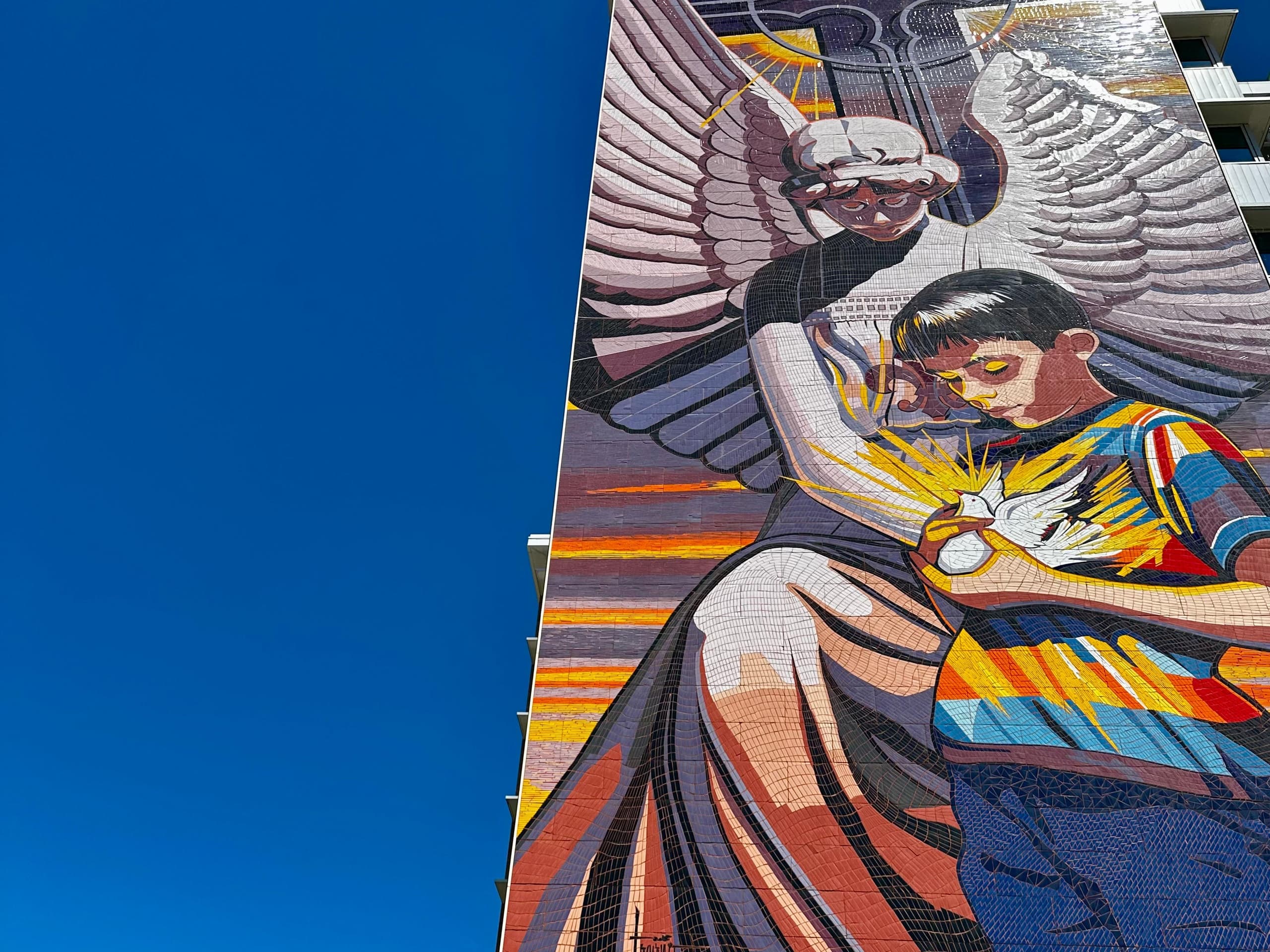 Large street mural of angel and child on downtown building