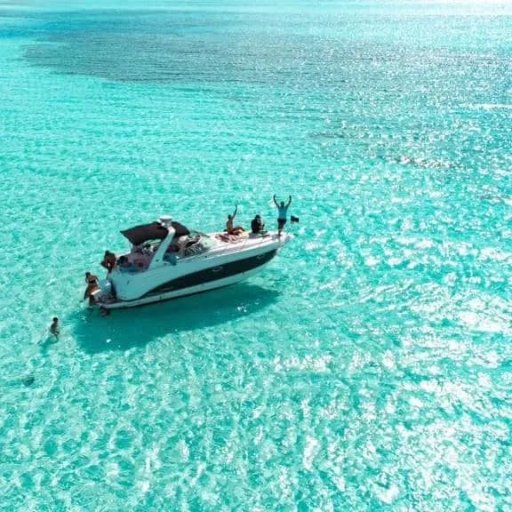 Aerial boat over crystal turquoise shallow waters, tropical