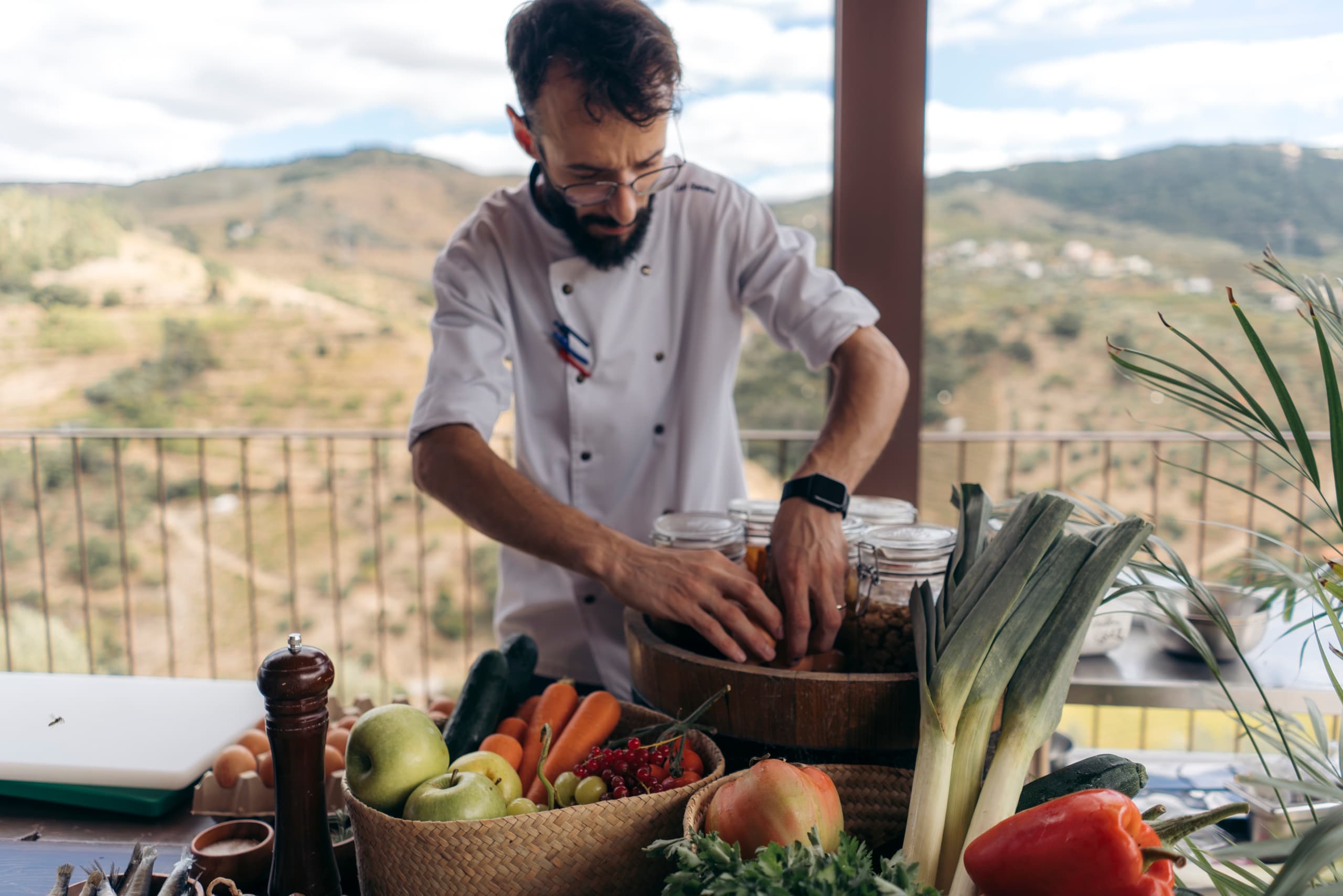 Chef prepping local produce outdoors with mountain views