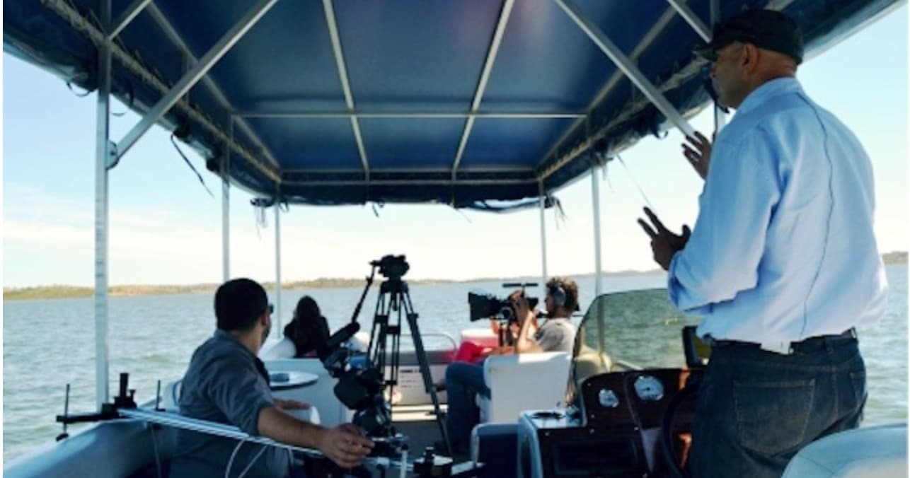 Guided boat tour under canopy with crew and camera gear