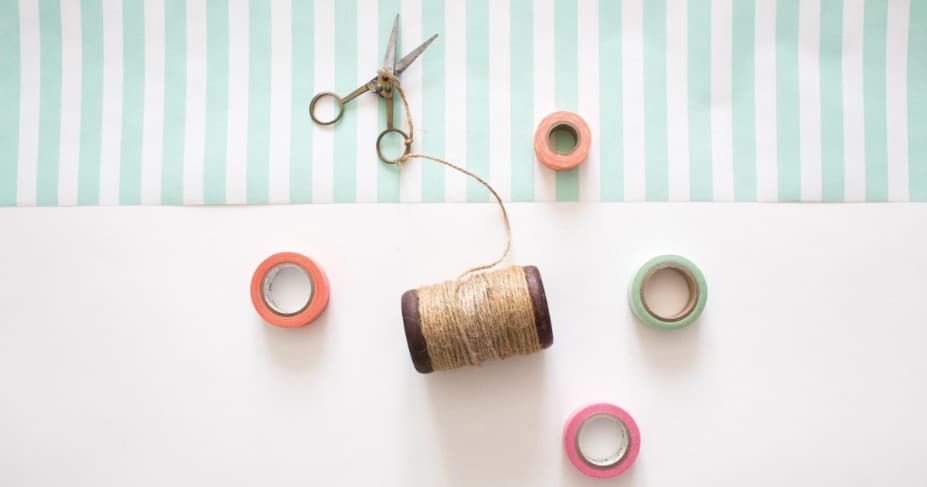 Colorful thread spools flatlay on striped crafting workspace