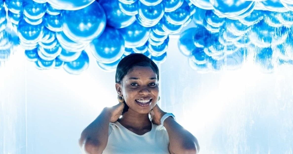 Woman smiling under blue balloons in indoor photo studio setting