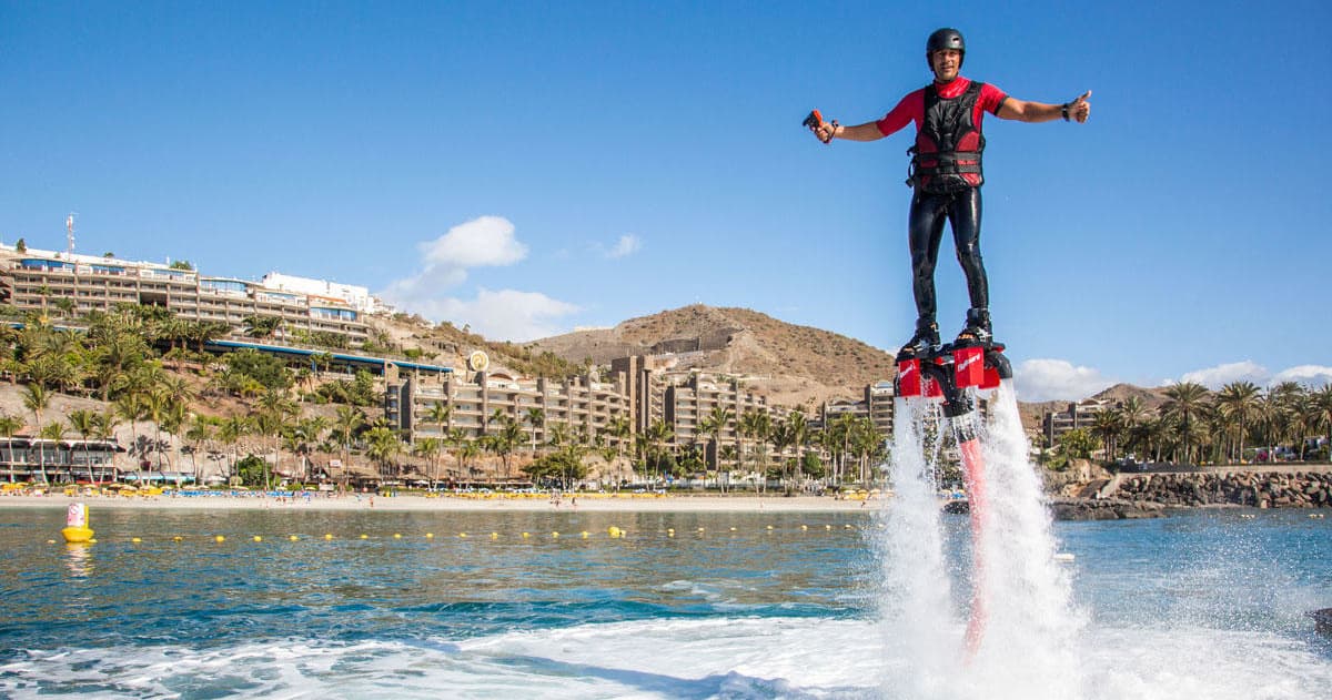 Flyboarder propelled above sea near marina showing water thrust