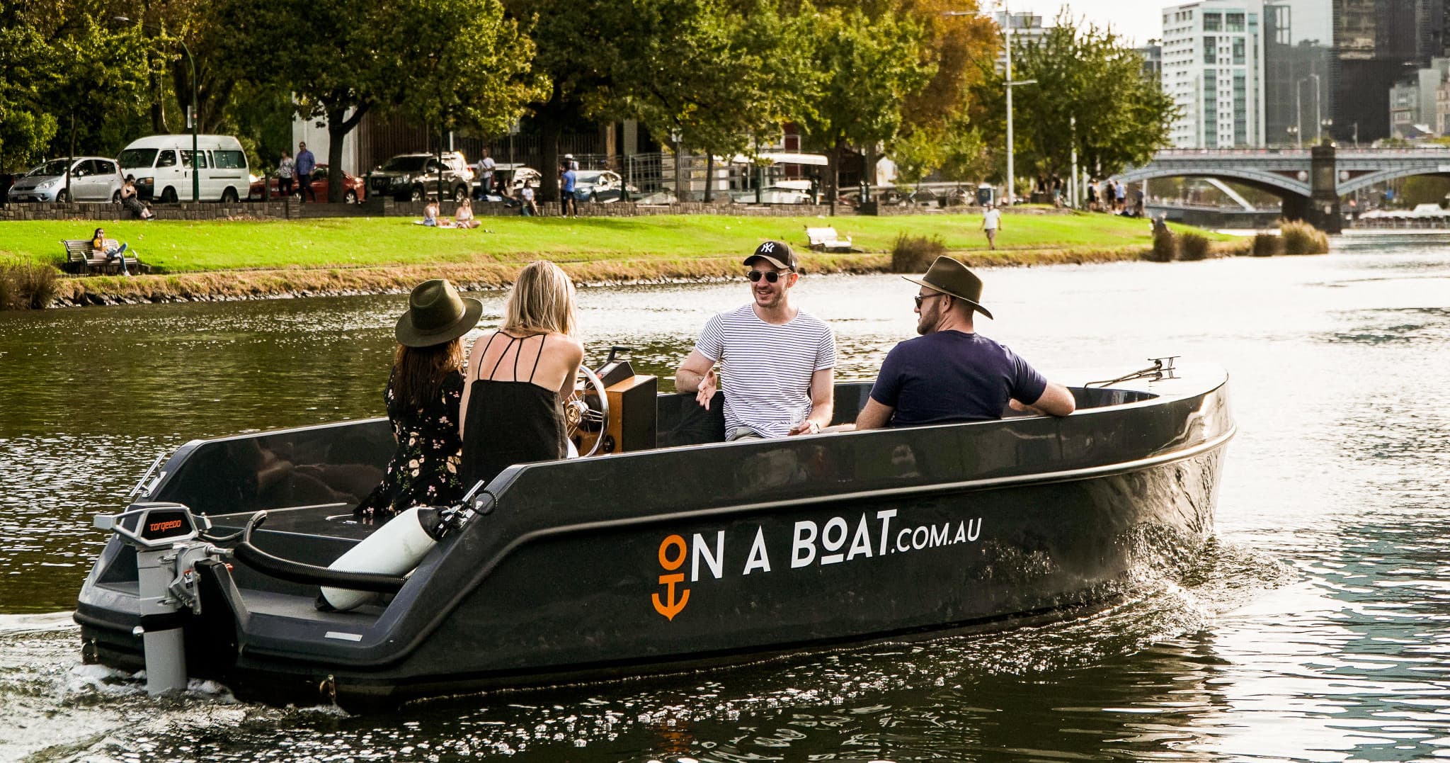 Small private boat cruising river with park shoreline