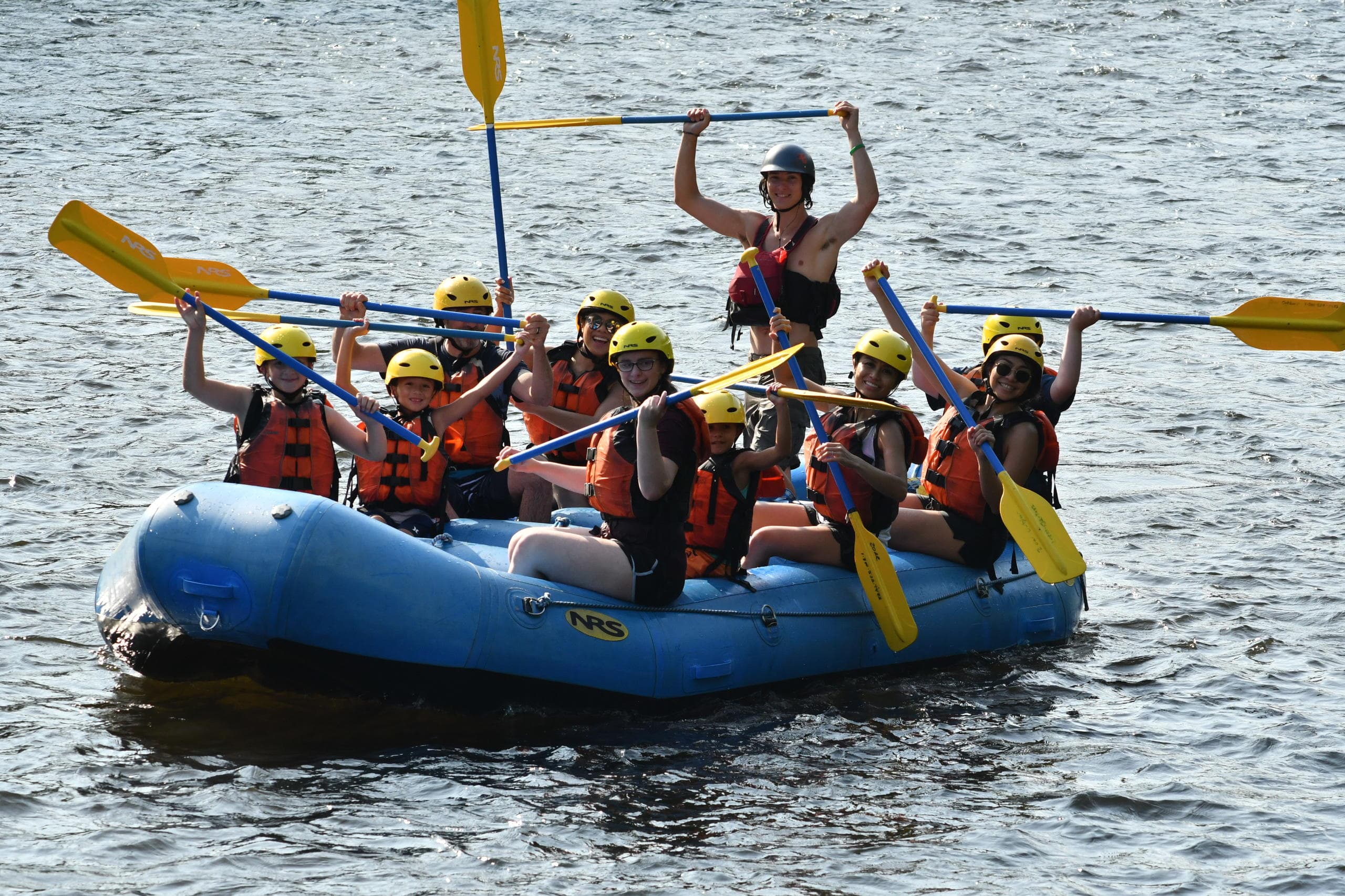 Excited rafters paddling a blue raft through churning whitewater