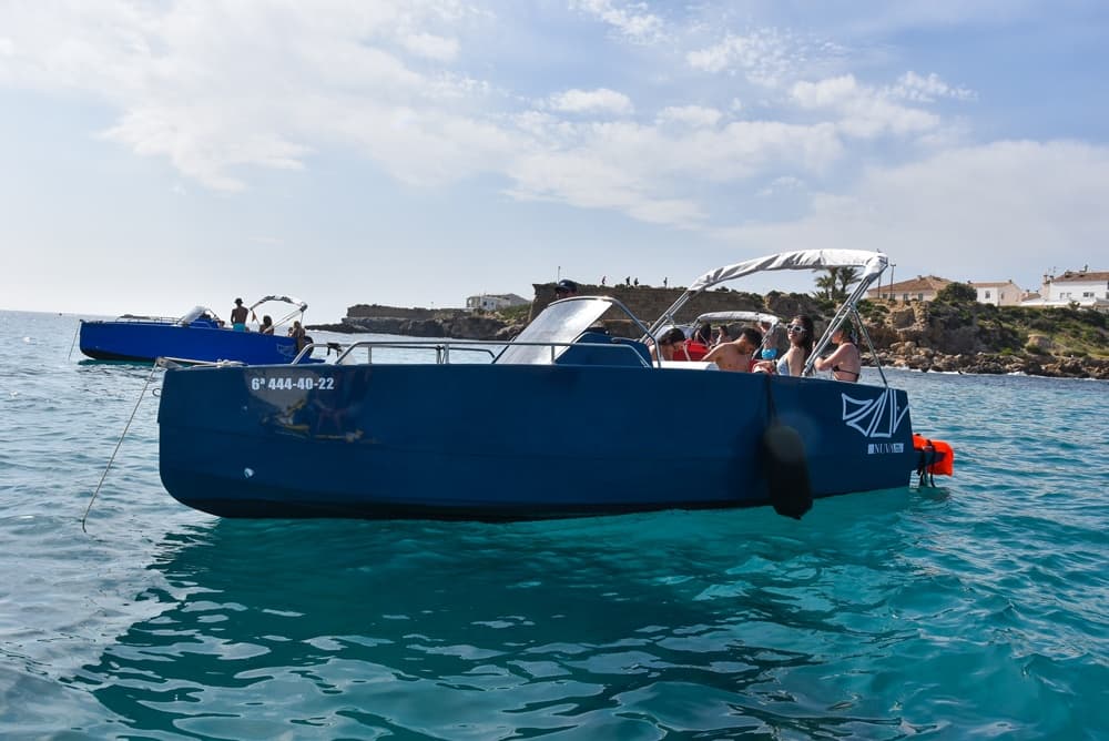 Coastal day boat with passengers on clear turquoise sea