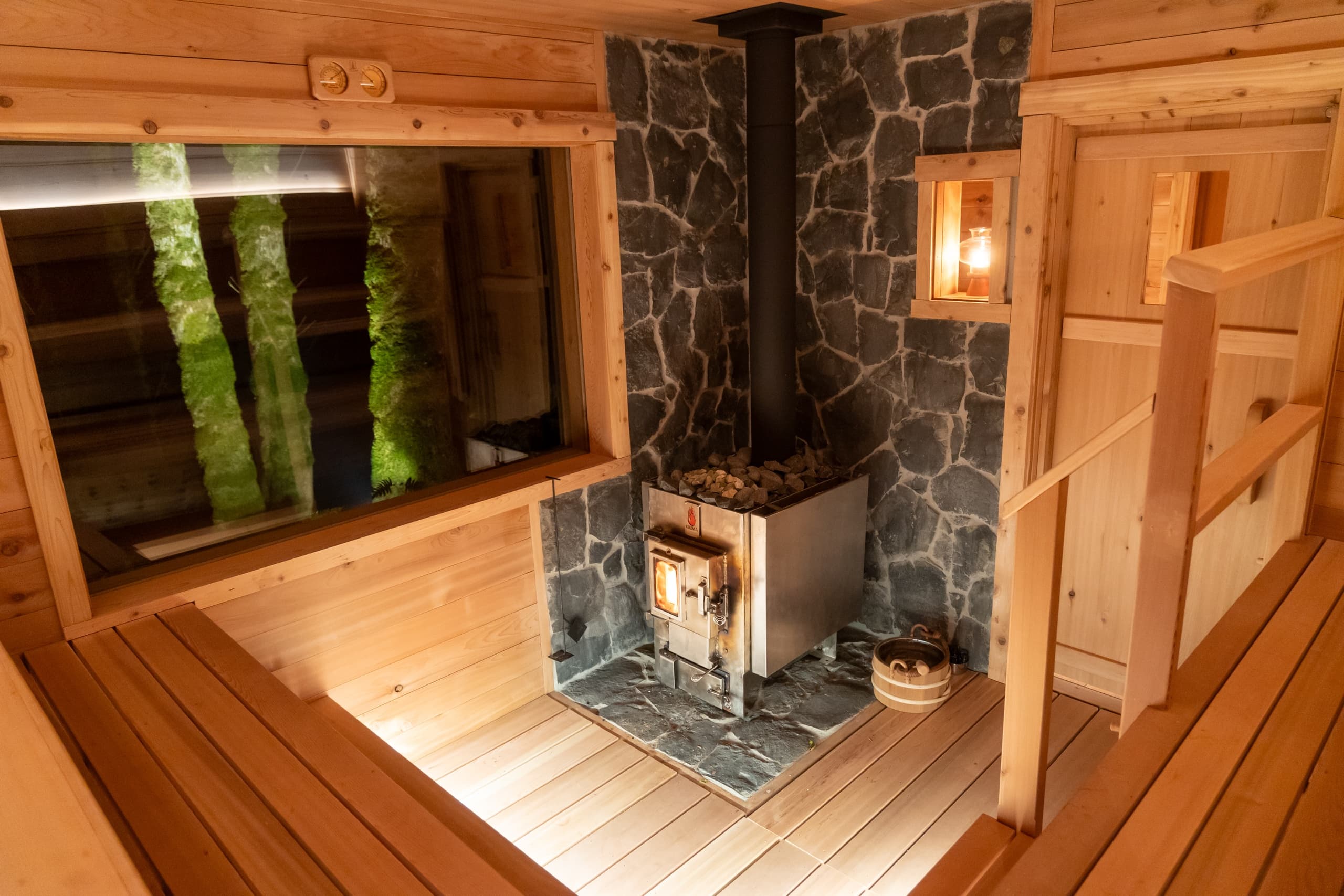 Wood-fired sauna stove and cedar benches inside rustic sauna room