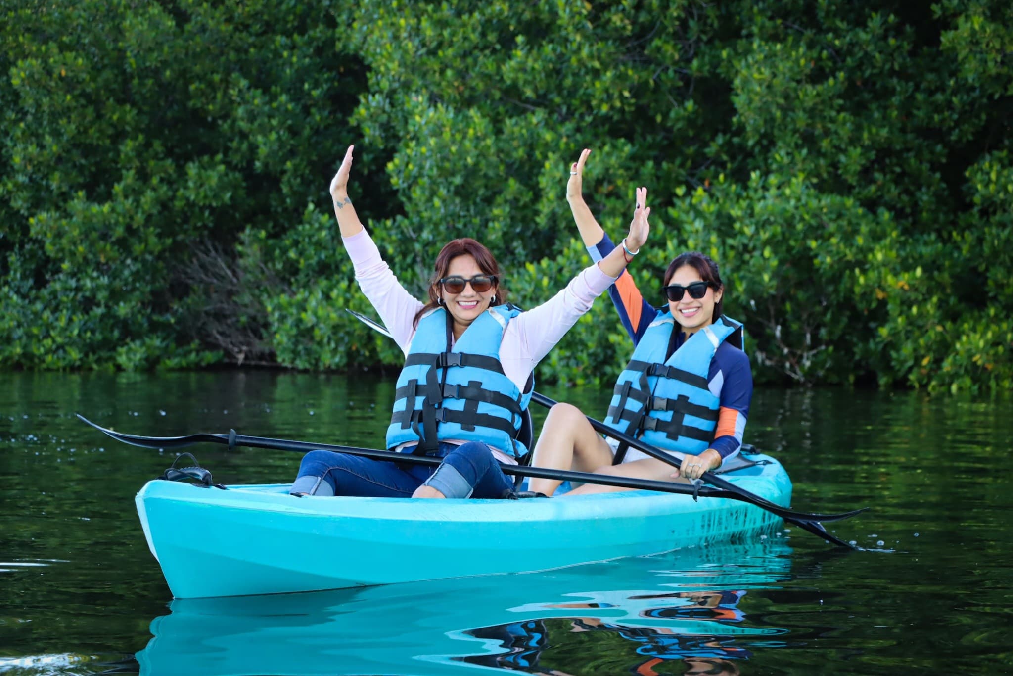Group of kayakers in turquoise kayaks exploring mangrove canals