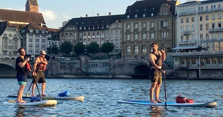 Paddleboarders touring along city waterfront at golden hour