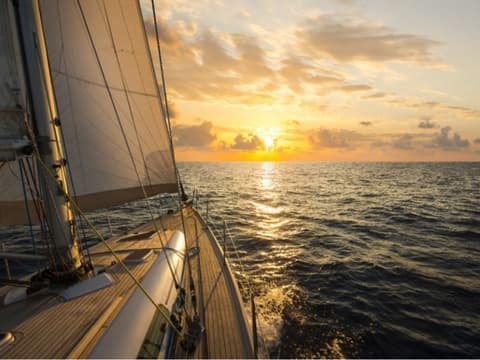 Sailboat cruising at sunset on open ocean, deck view