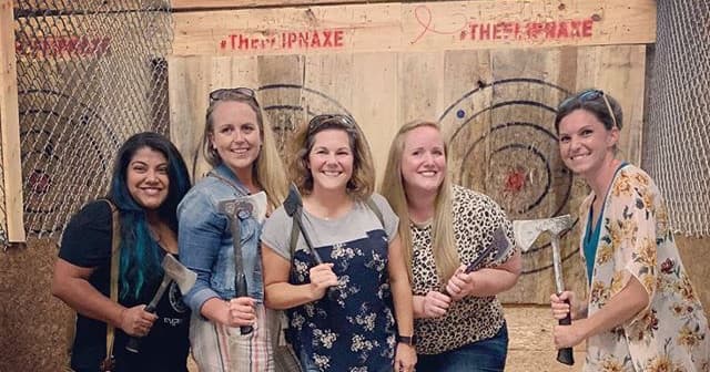 Group of five women holding axes at indoor target boards