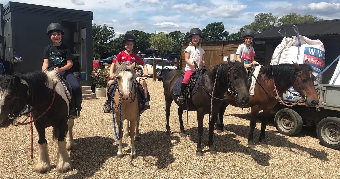 Children on ponies lined up at an outdoor riding center