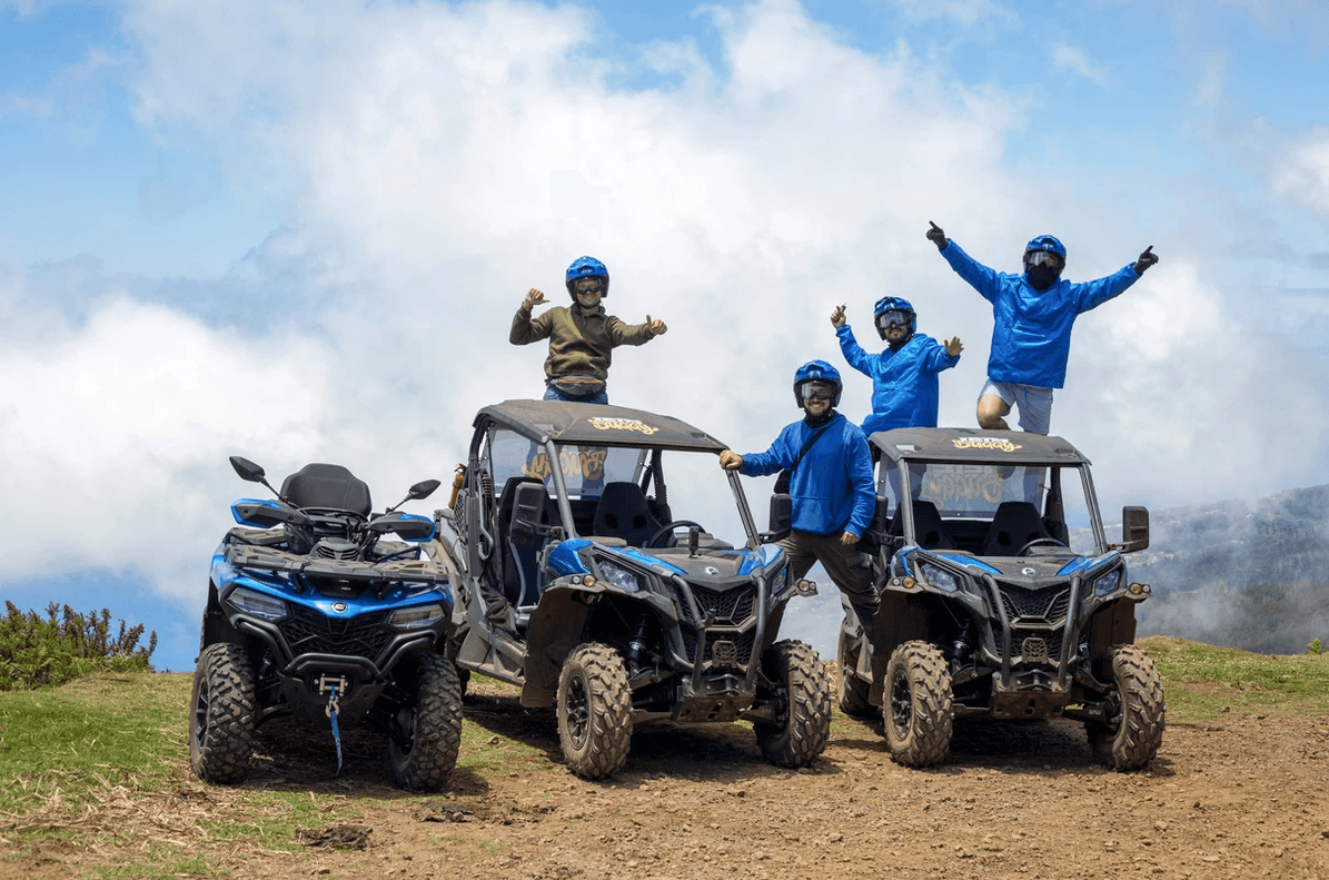 Three off-road buggies with riders on a mountain trail, coastal vista