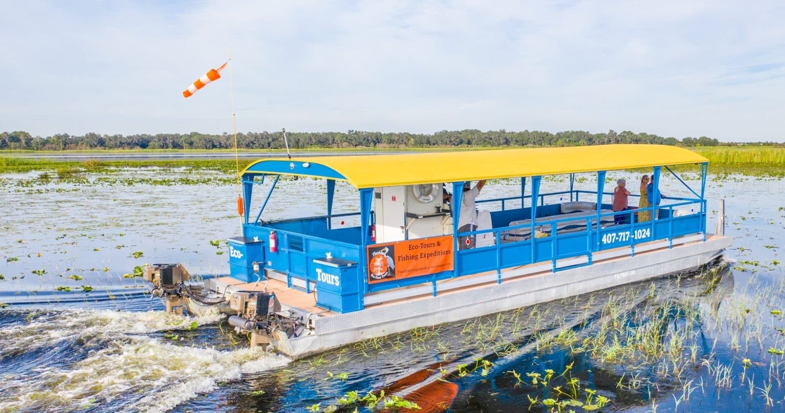 Eco pontoon boat touring Everglades marshes, passengers viewing wildlife