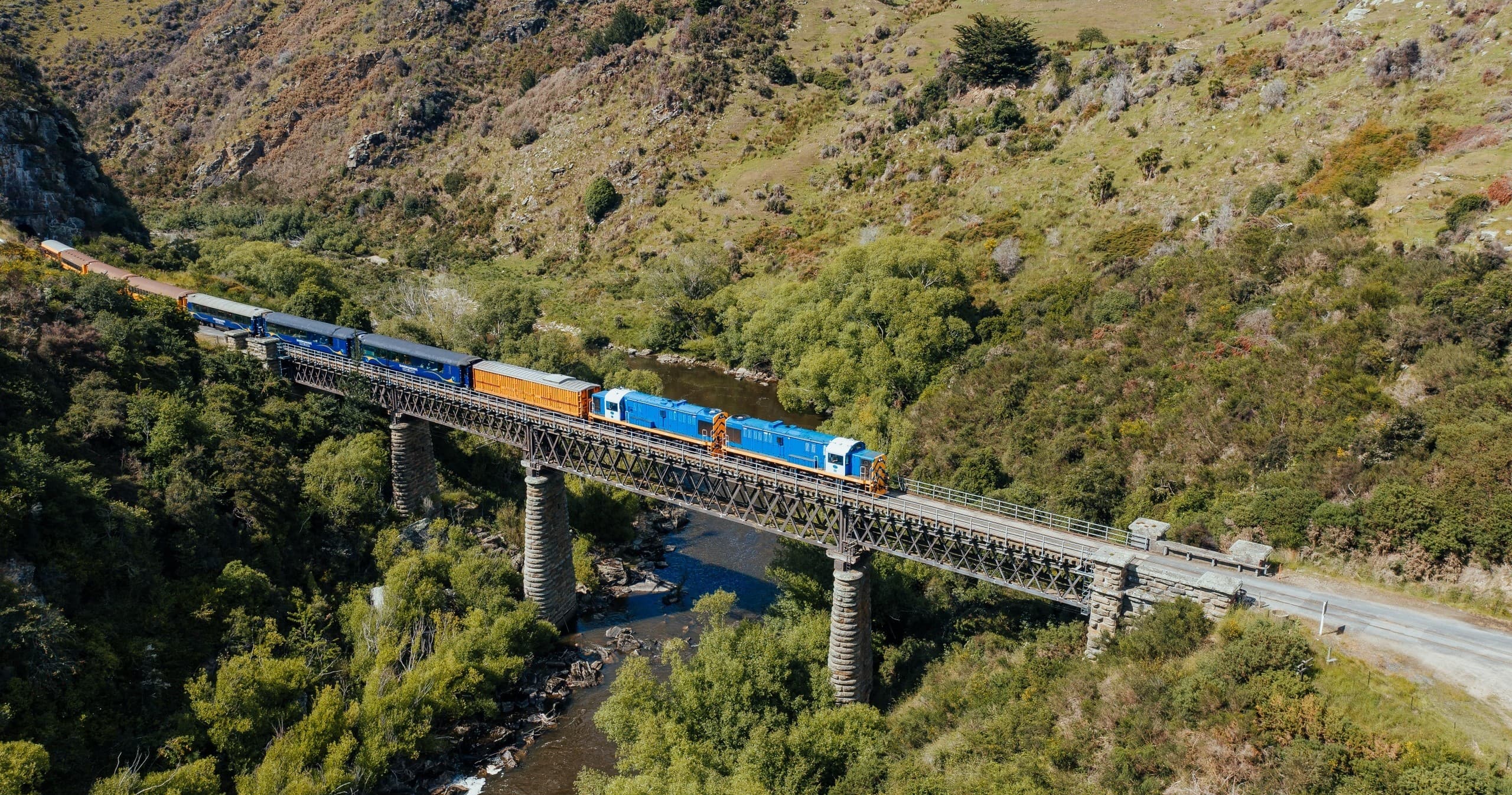 Scenic train traversing high viaduct across green river valley