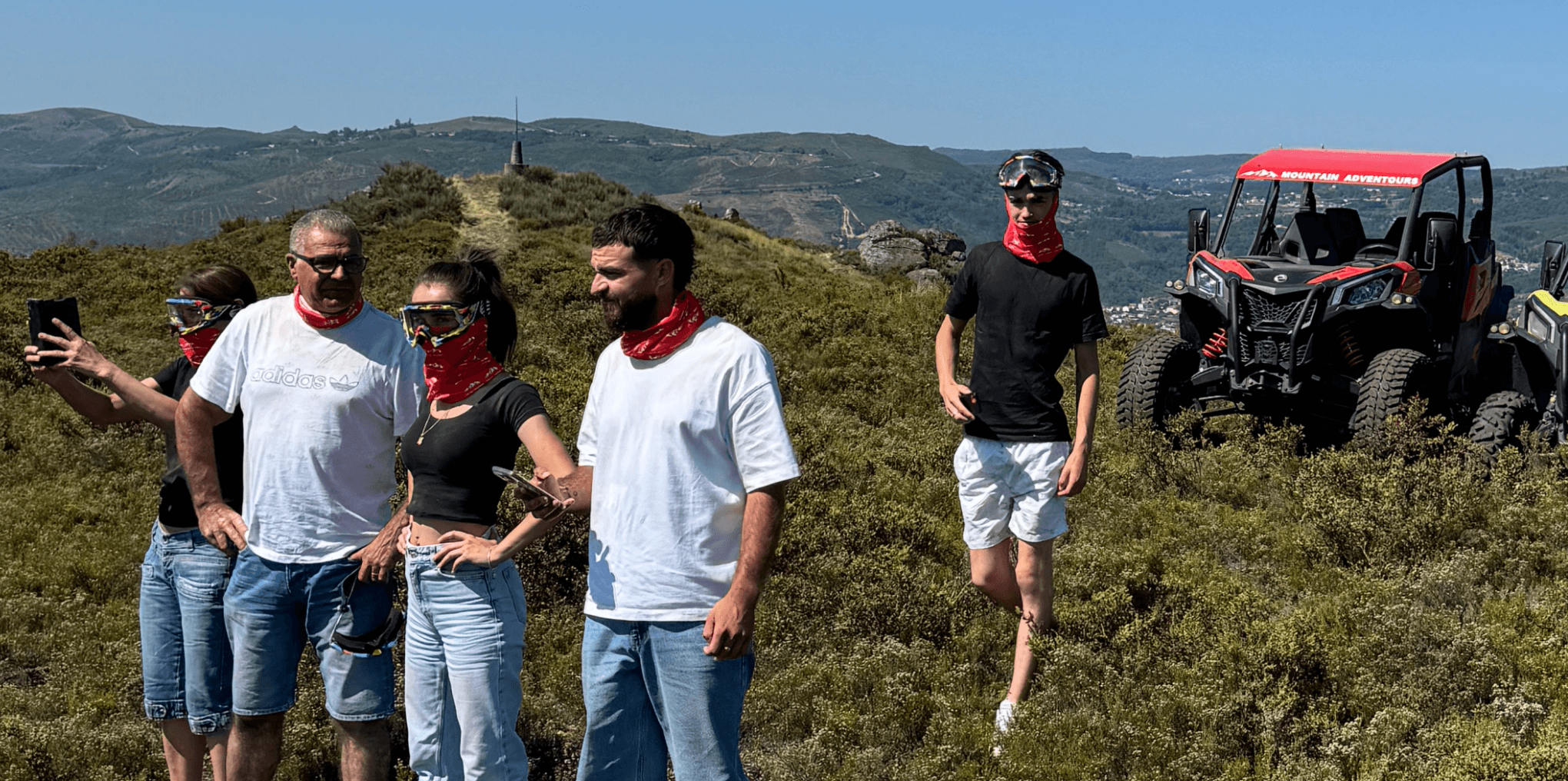 Group of adventurers with UTVs on scenic hilltop trail