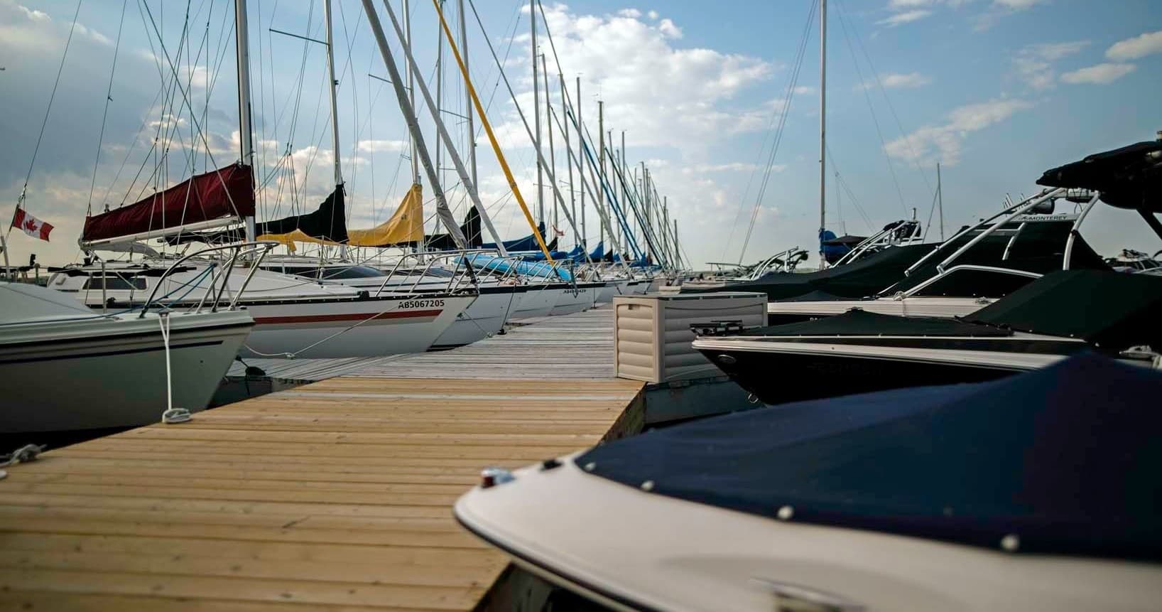 Row of docked recreational boats along wooden marina pier