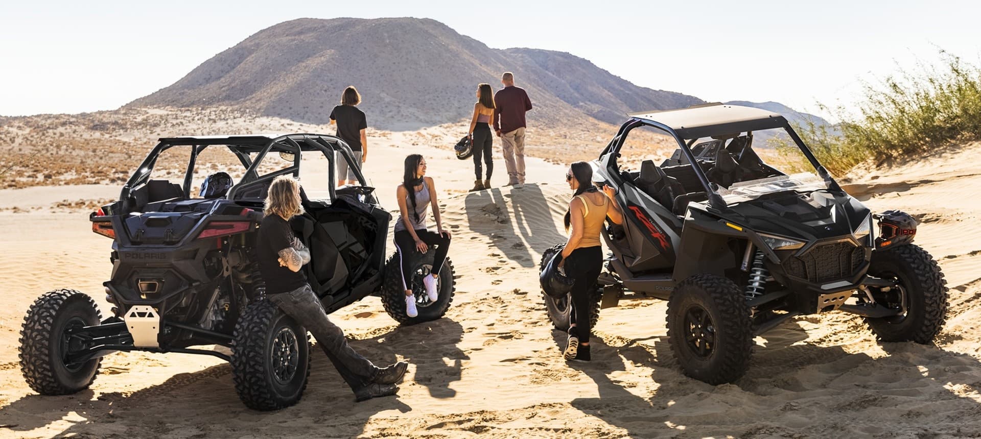 Group of riders and UTVs gathering on sandy desert dunes