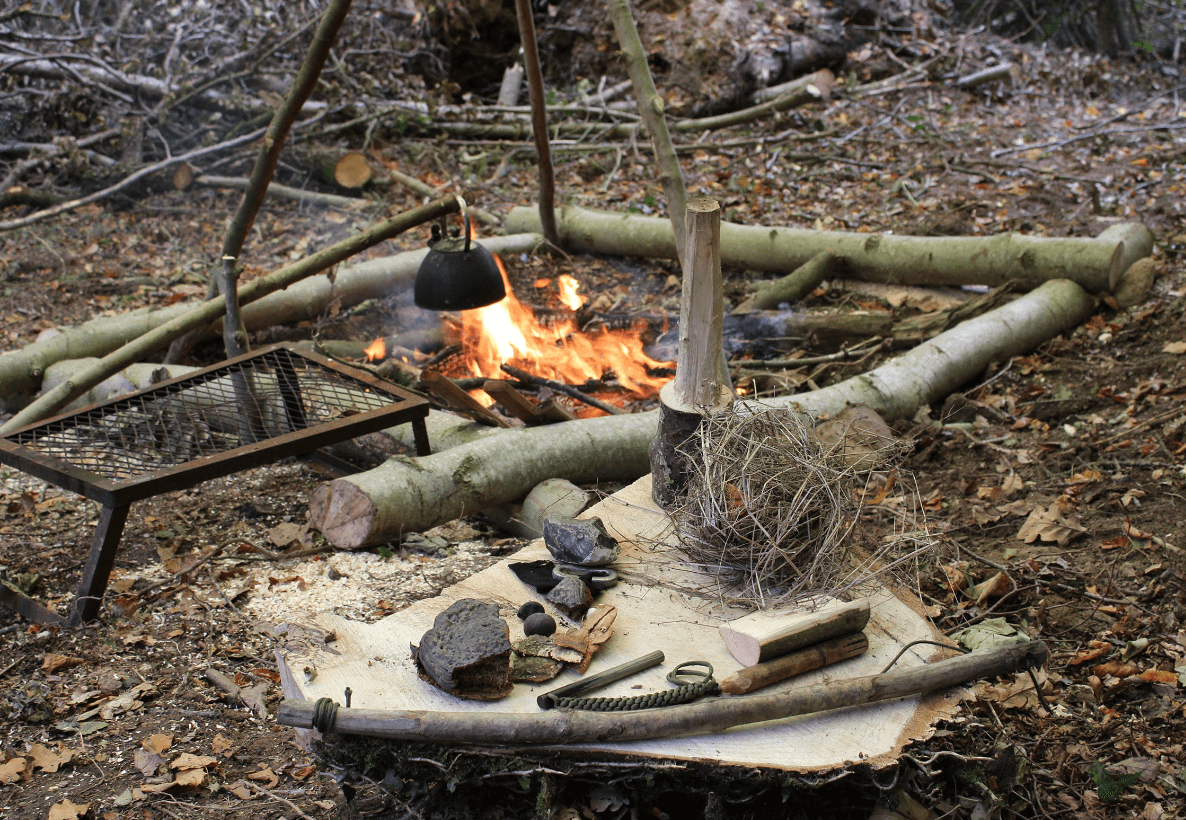 Woodland bushcraft campfire setup with tools and shelter