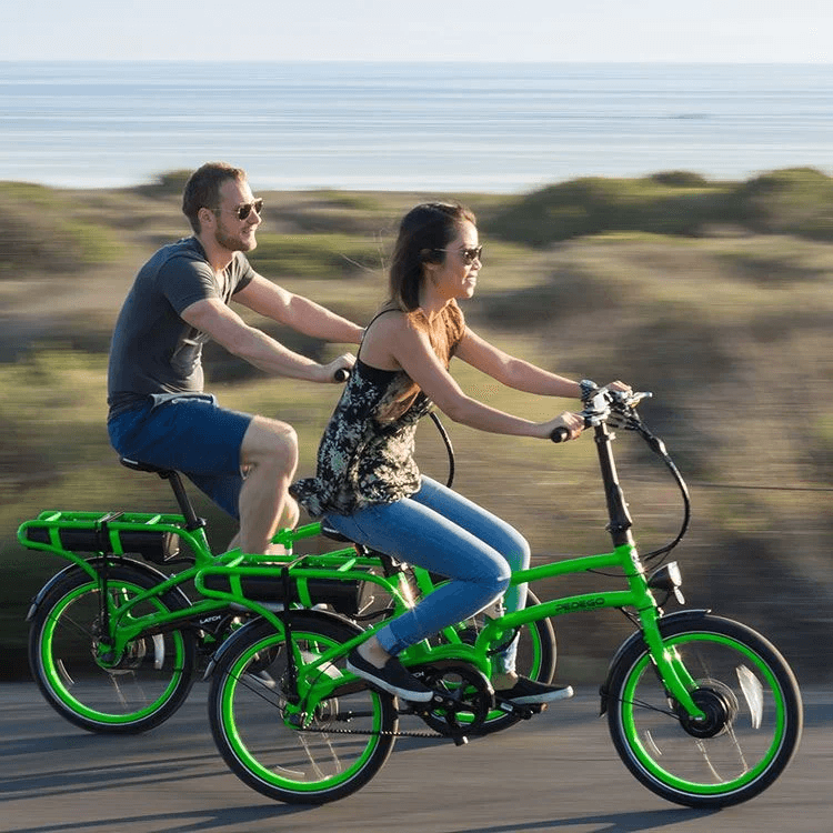 Couple riding electric bikes along scenic coastal road