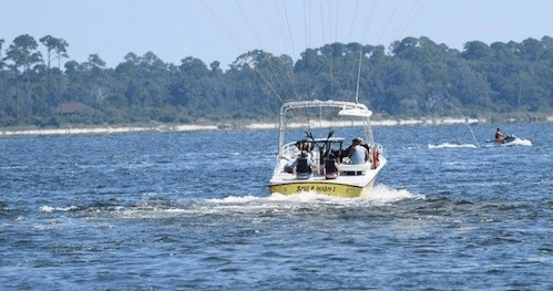 Parasailing behind powerboat over coastal bay waters