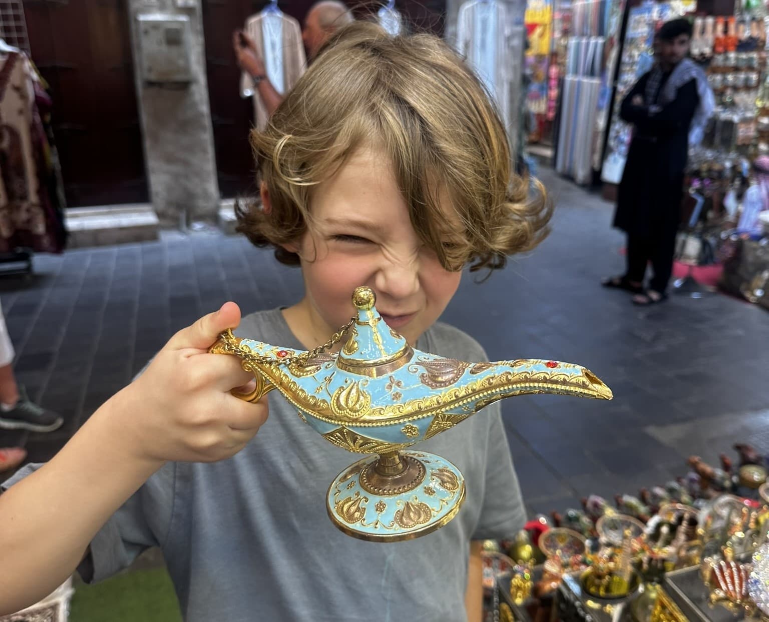 Child holding decorative brass lamp at Middle Eastern souk stall