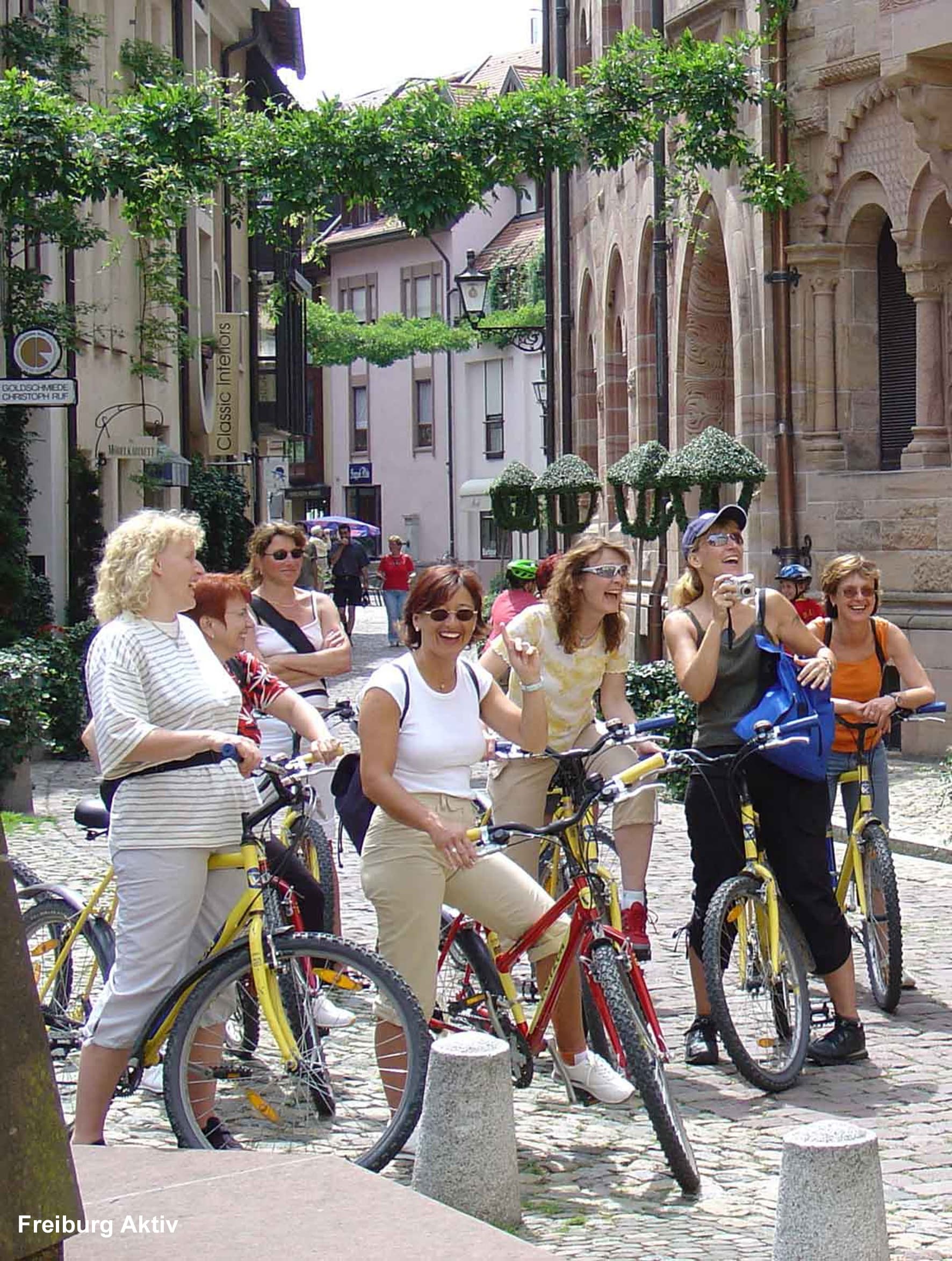 Women cyclists pausing in narrow old-town street on tour