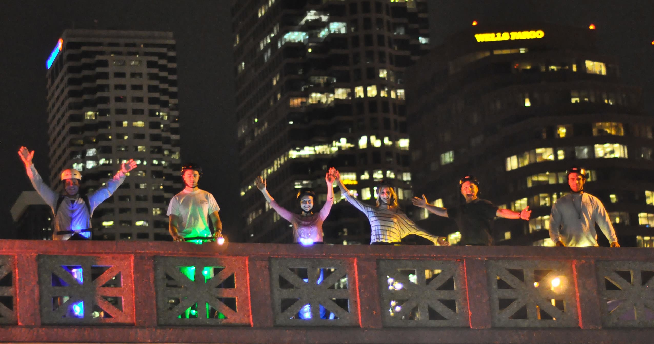 Night Segway tour on lit city bridge with skyline lights