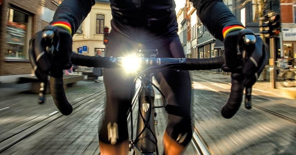 Cyclist gripping handlebars riding fast through city at night