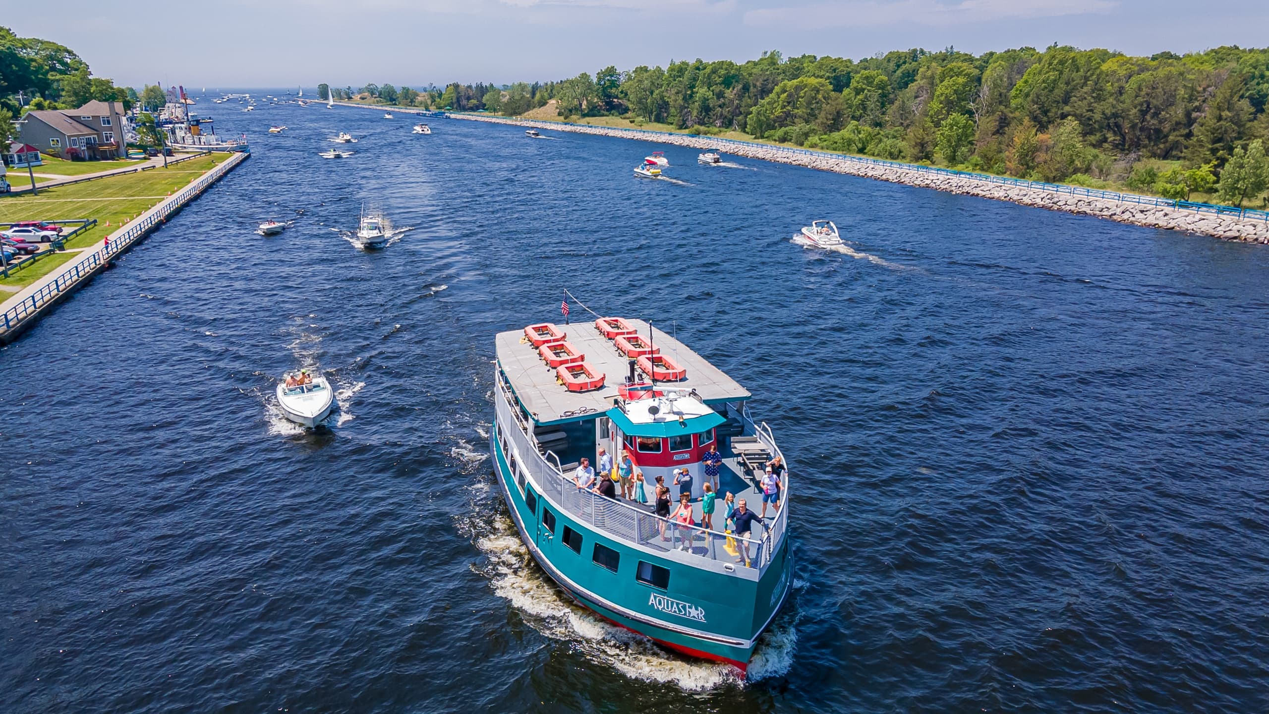 Aerial tour boat cruising inland waterway with shoreline