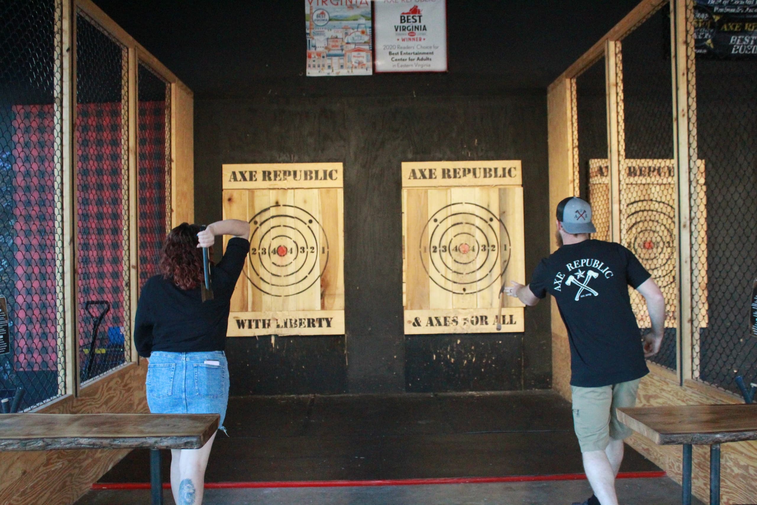 Two people throwing axes toward targets in indoor axe lanes