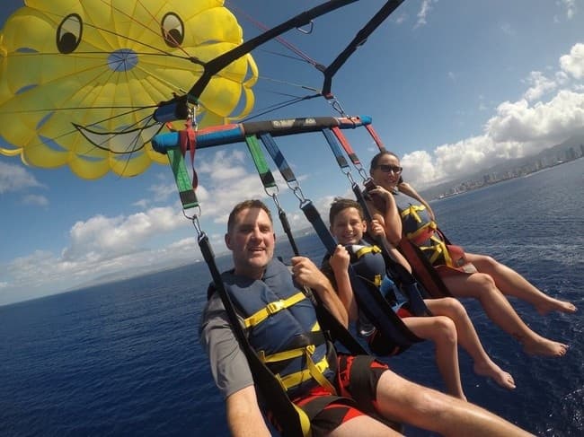 Three people parasailing over Waikiki ocean with clear sky