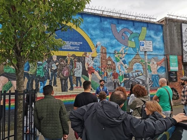 Street mural tour with guide and crowd viewing political mural in Belfast
