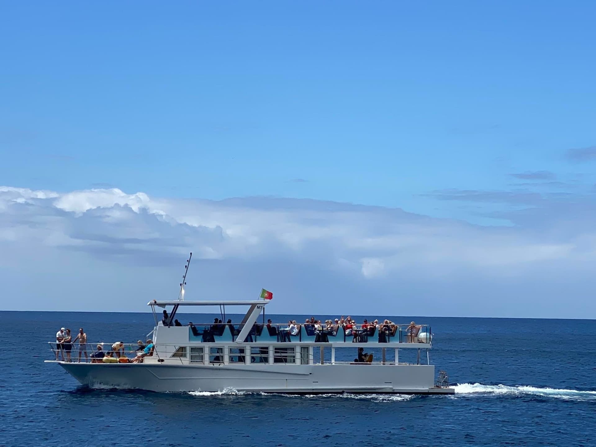 Tour boat cruising on open ocean with passengers at midday