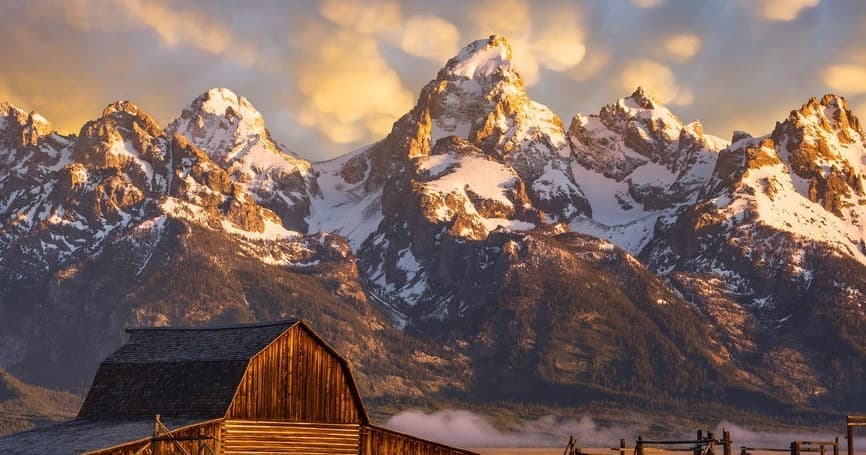 Rustic barn foreground with Grand Teton mountains at sunrise