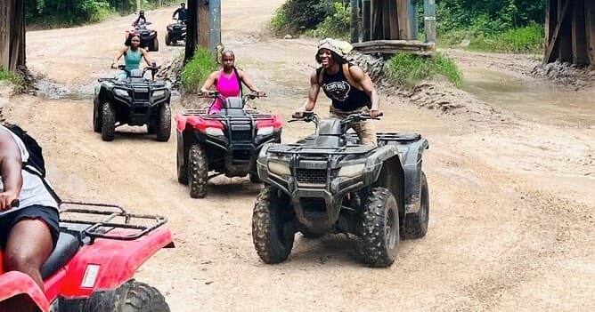 Group riding ATVs on muddy trail through tropical forest tour