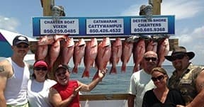 Charter group smiling beneath a rack of red snapper, Destin waters