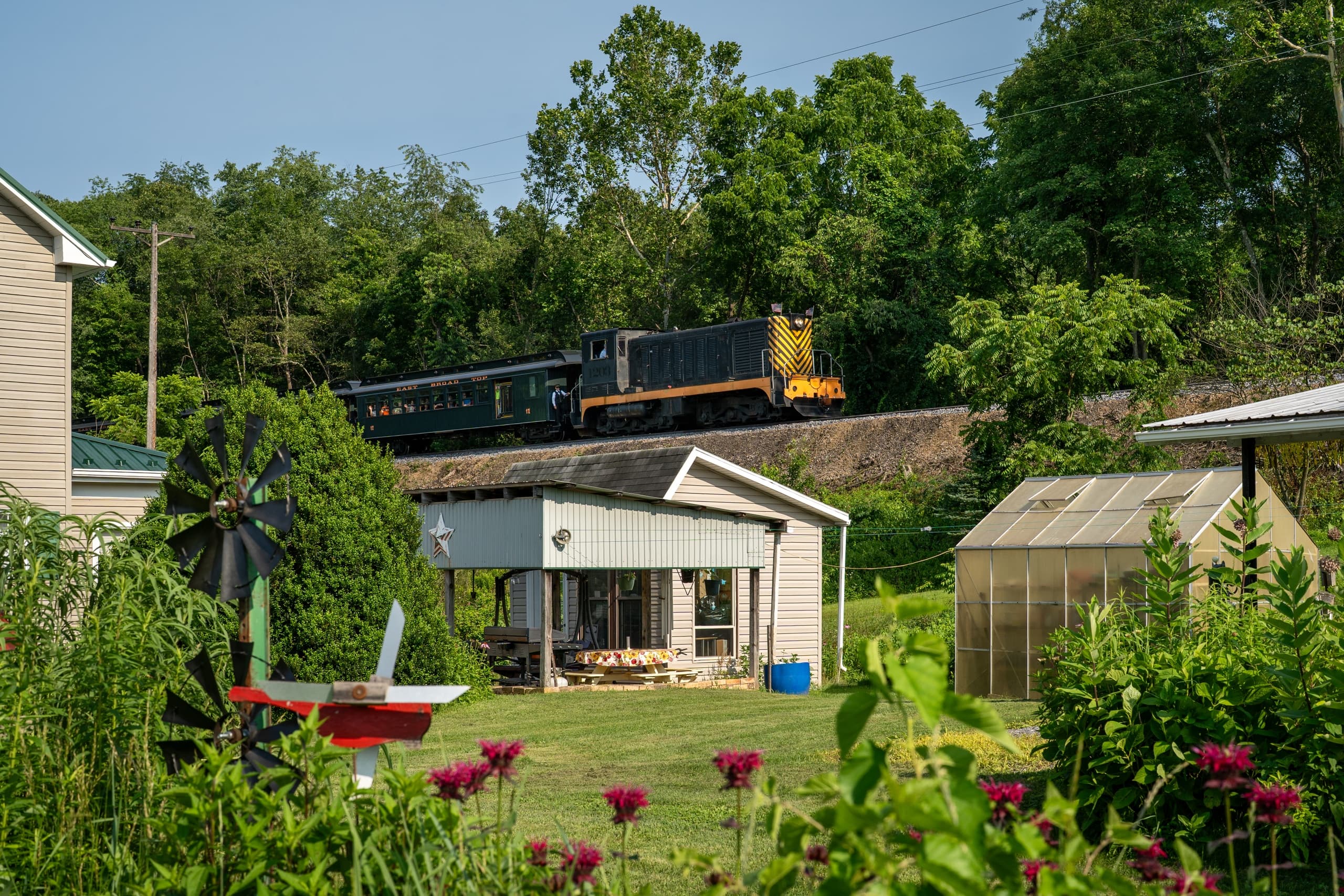 Steam locomotive passing rural homesteads across summer fields