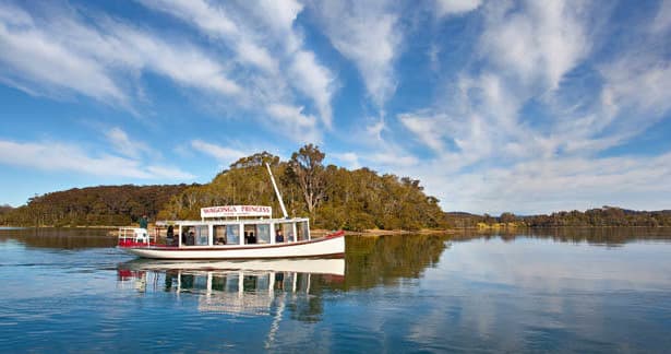 Scenic inlet cruise boat on calm river with dramatic sky