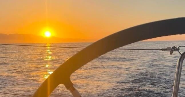 Sailing at sunset with ocean horizon viewed from boat helm