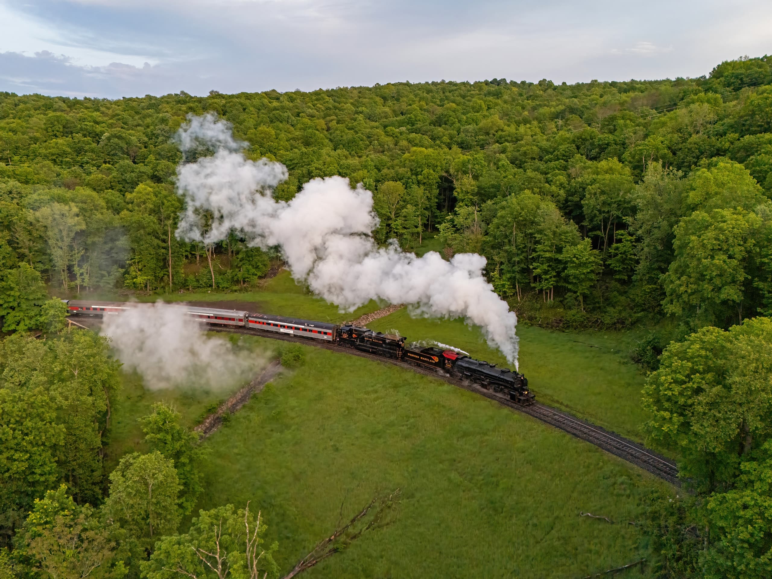 Steam train cruising through green forested hills scenic ride