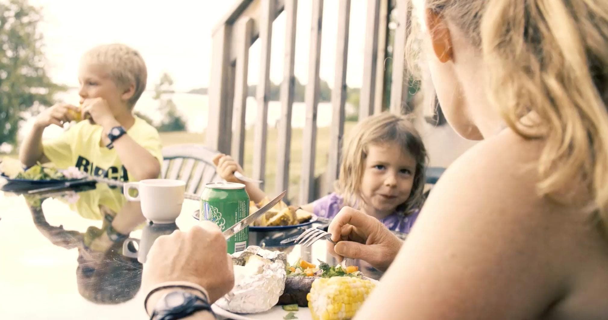 Family enjoying outdoor deck meal and kids eating by railing