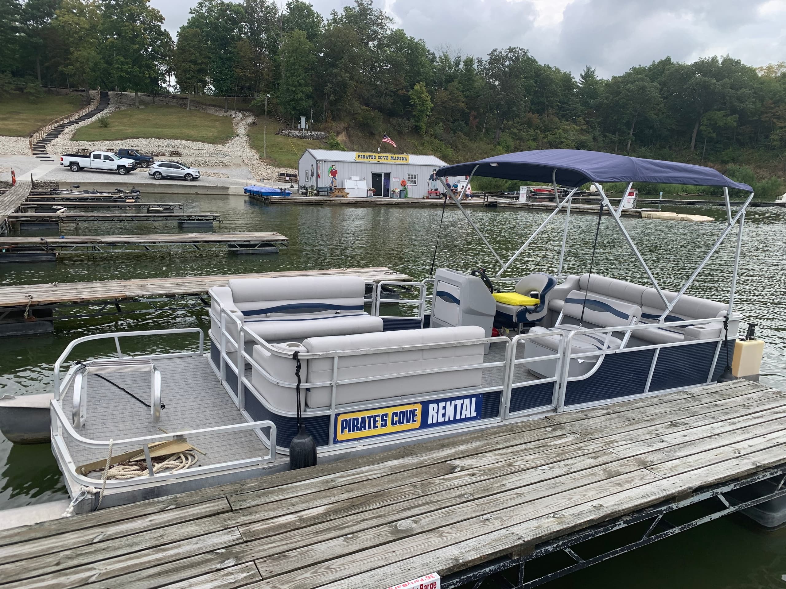 Sunlit pontoon boat docked on calm lake for rentals