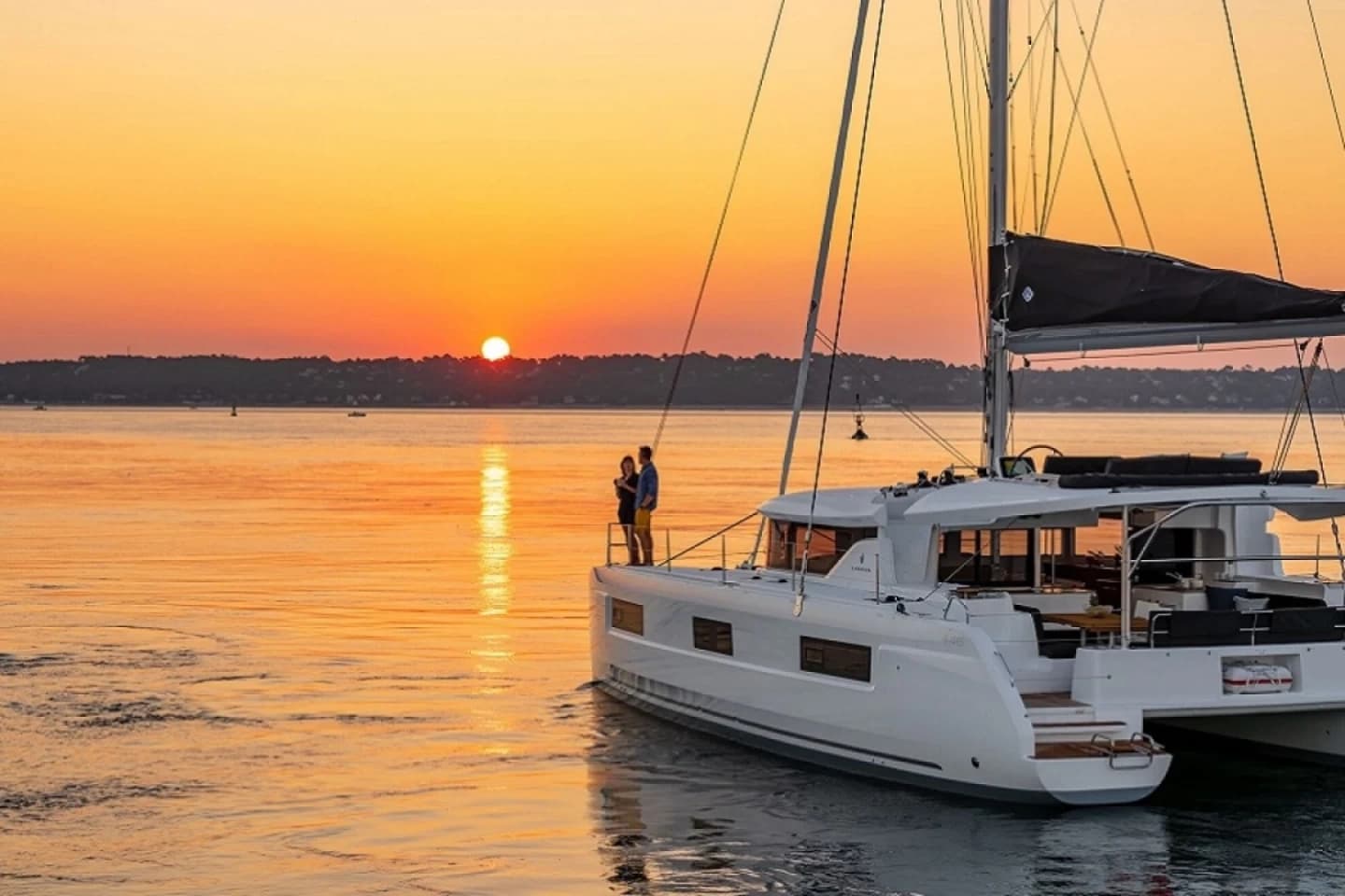 Catamaran sailing at sunset on calm coastal bay, romantic cruise