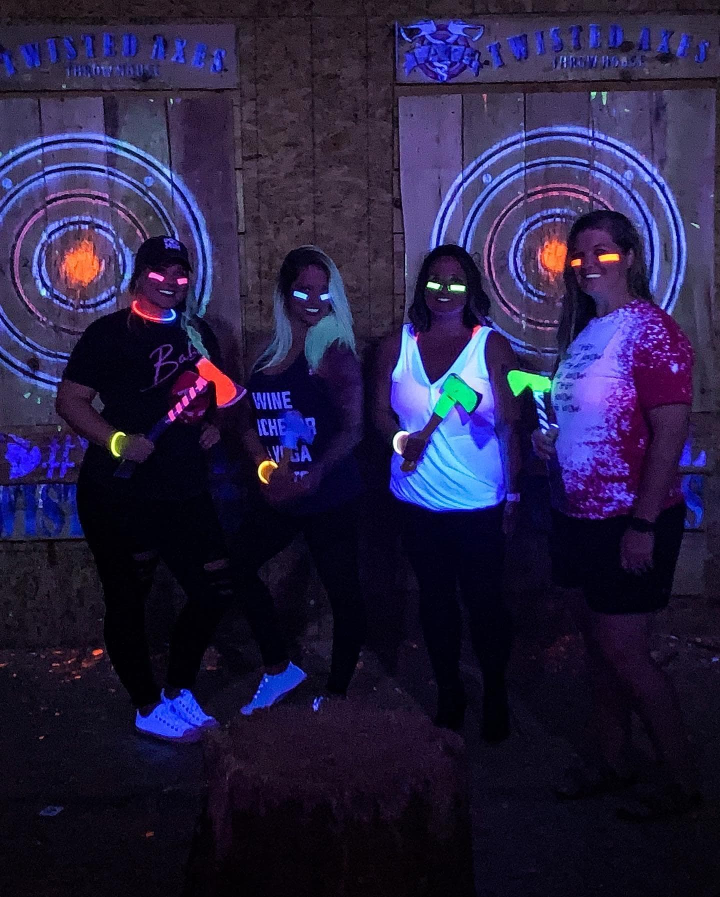 Group with glow axes under blacklight at indoor lanes