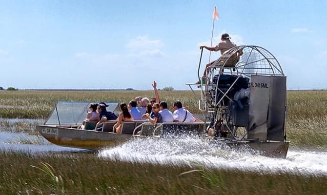 Airboat tour skimming Florida Everglades marsh with passengers